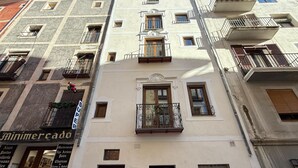A multi-story building with balconies, a visible storefront with a sign, and a door. - Mirador Del Rey (Cuenca)