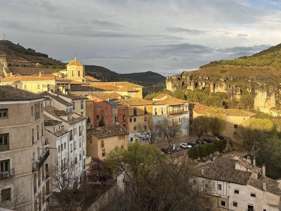 A historic town with traditional architecture, including a church with a bell tower and a cathedral with a large rose window.