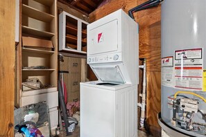 A room with a white water heater, a wooden cabinet, and a large water tank.