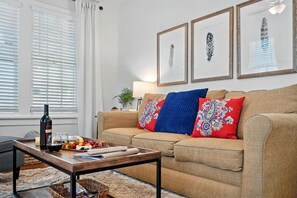A living room with a sofa, a coffee table, a lamp, and framed artwork on the wall.