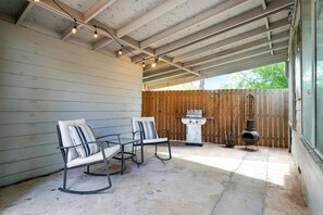 An outdoor patio with two rocking chairs, a grill, and a decorative pot.