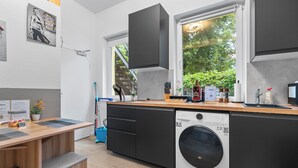 A modern kitchen with a built-in dishwasher, a wooden countertop, and a window with a view of greenery. - Apartment Cologne City (köln)
