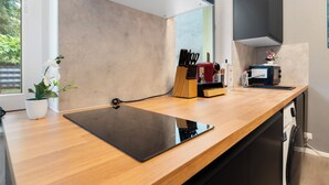 A modern kitchen with a wooden countertop, a black cutting board, a knife block, and a coffee machine. - Apartment Cologne City (köln)