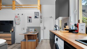 A modern kitchen with wooden countertops, a built-in dishwasher, and a dining area with a bench. - Apartment Cologne City (köln)