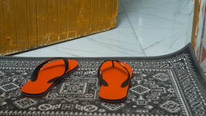 A pair of orange flip-flops on a patterned doormat. - Breflection Spa and Hostel (Zanzibar Town)