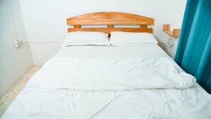 A bed with a wooden headboard, white bedding, and a blue curtain. - Breflection Spa and Hostel (Zanzibar Town)