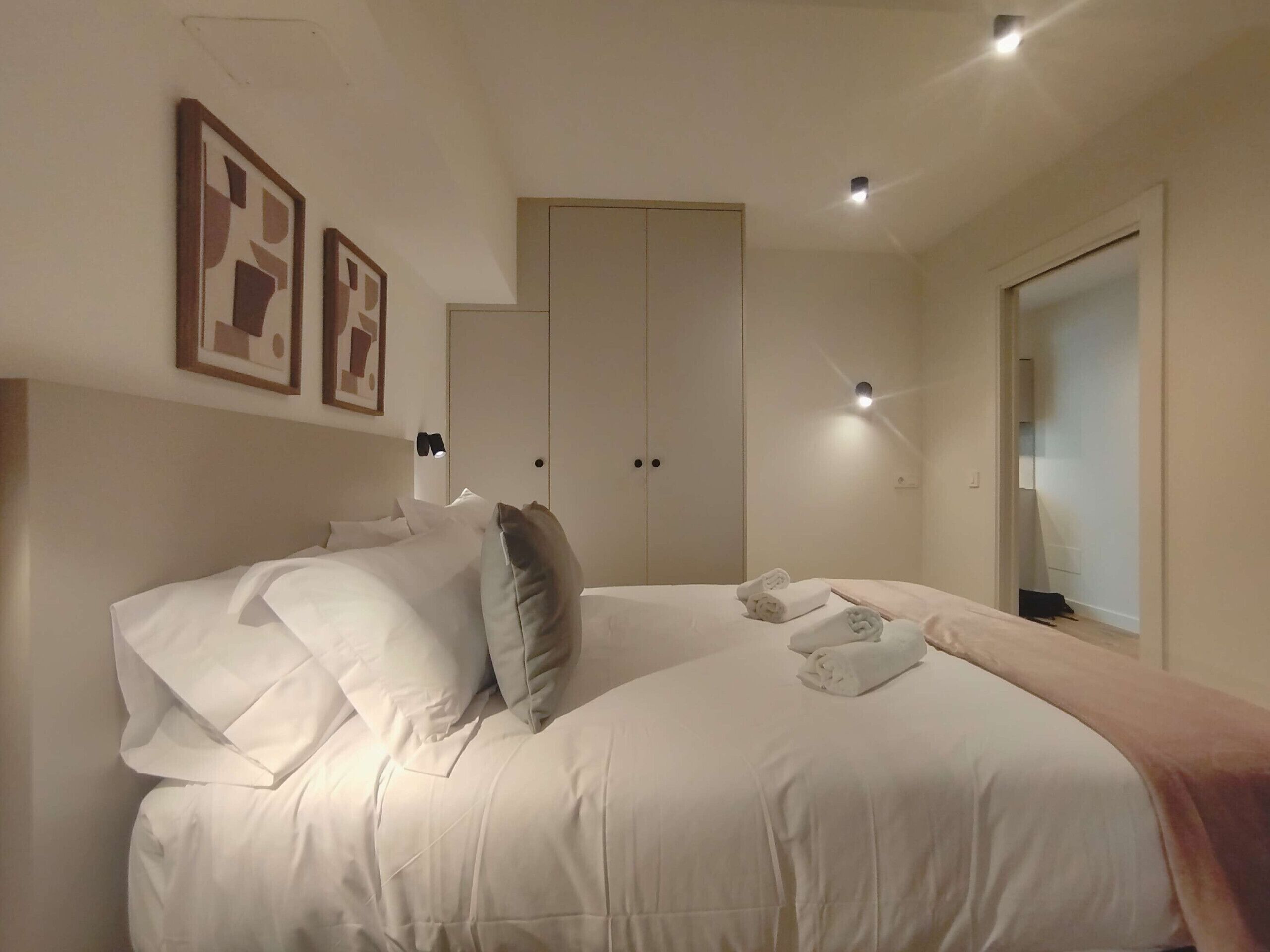 A bedroom with a large bed, a wardrobe, and a mirror.