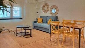 Un salon moderne avec un canapé, une table à manger et des chaises, ainsi qu’une petite table d’appoint.