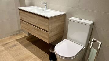 Uma casa de banho moderna com toucador de madeira, uma sanita branca e uma casa de wc.