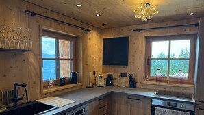 Eine moderne Küche mit Holzausstattung, einem eingebauten Geschirrspüler, einem Herd und einem großen Fenster mit Blick ins Freie.