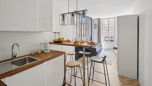 A modern kitchen with a wooden countertop, stainless steel sink, and bar stools. - Modern Central Paris Flat by Les Halles (Paris)