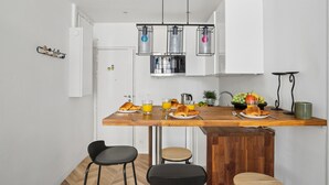 A modern kitchen with a wooden countertop, bar stools, and a hanging light fixture. - Modern Central Paris Flat by Les Halles (Paris)