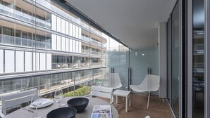 A modern dining area with a table set for two, two white chairs, and a glass table. - Waterfront Blue by Wonderful Italy (Genova)