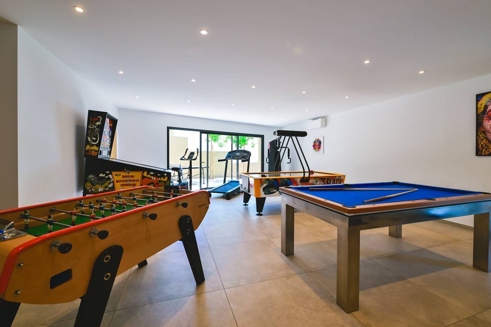 A recreational room with a foosball table, pool table, and exercise equipment.