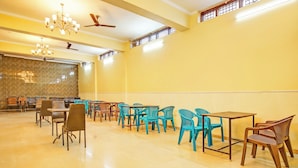 A spacious indoor area with multiple tables and chairs, ceiling fans, and a chandelier. - Hotel Kingstone Zirakpur (Zirakpur)