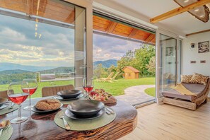 A dining area with a table set for two, a sofa, and a view of the outdoors. - Vineyard cottage Pri mali luži (Mokronog-Trebelno)