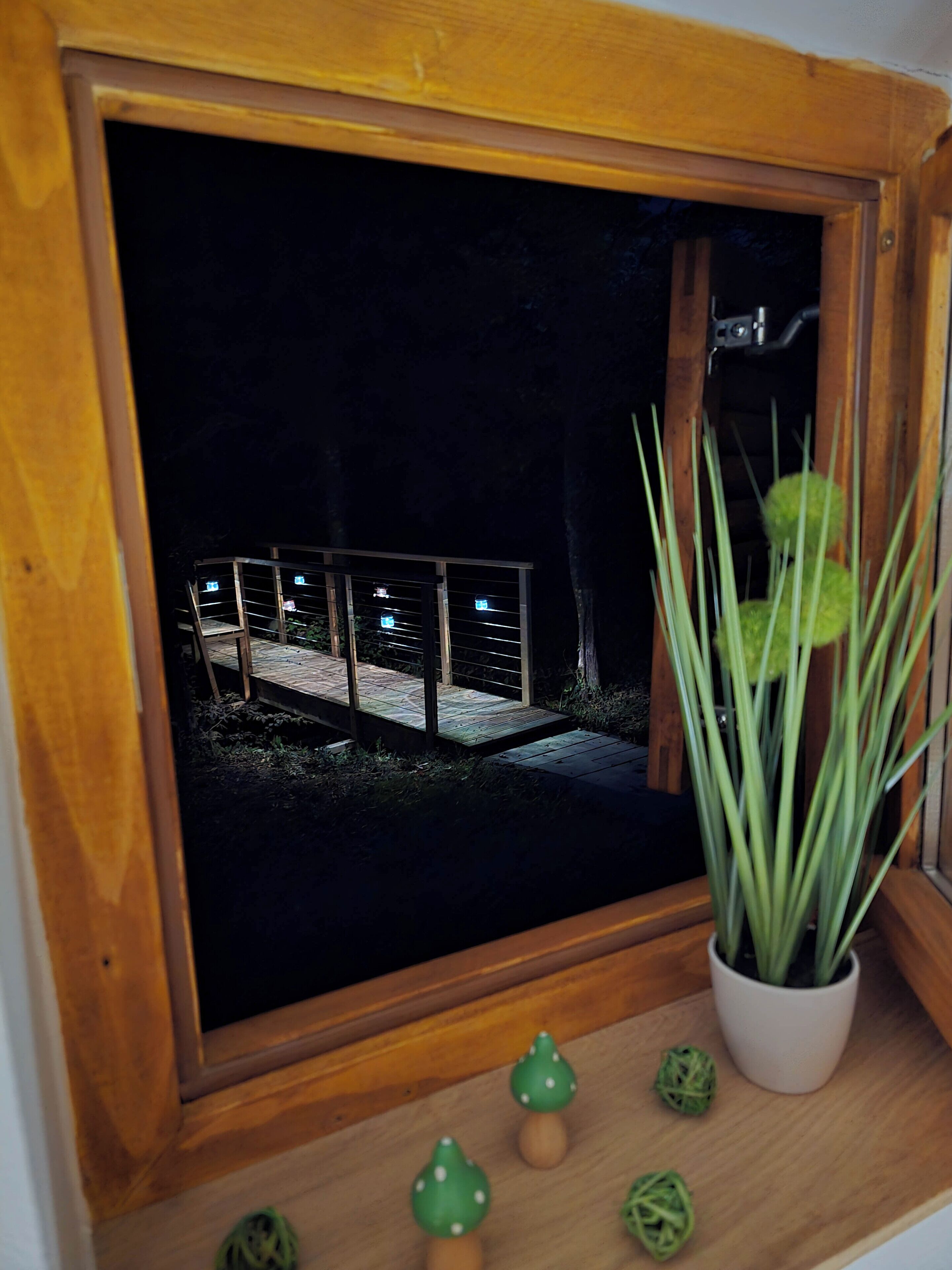 Una ventana con marco de madera y vista a un balcón de noche.