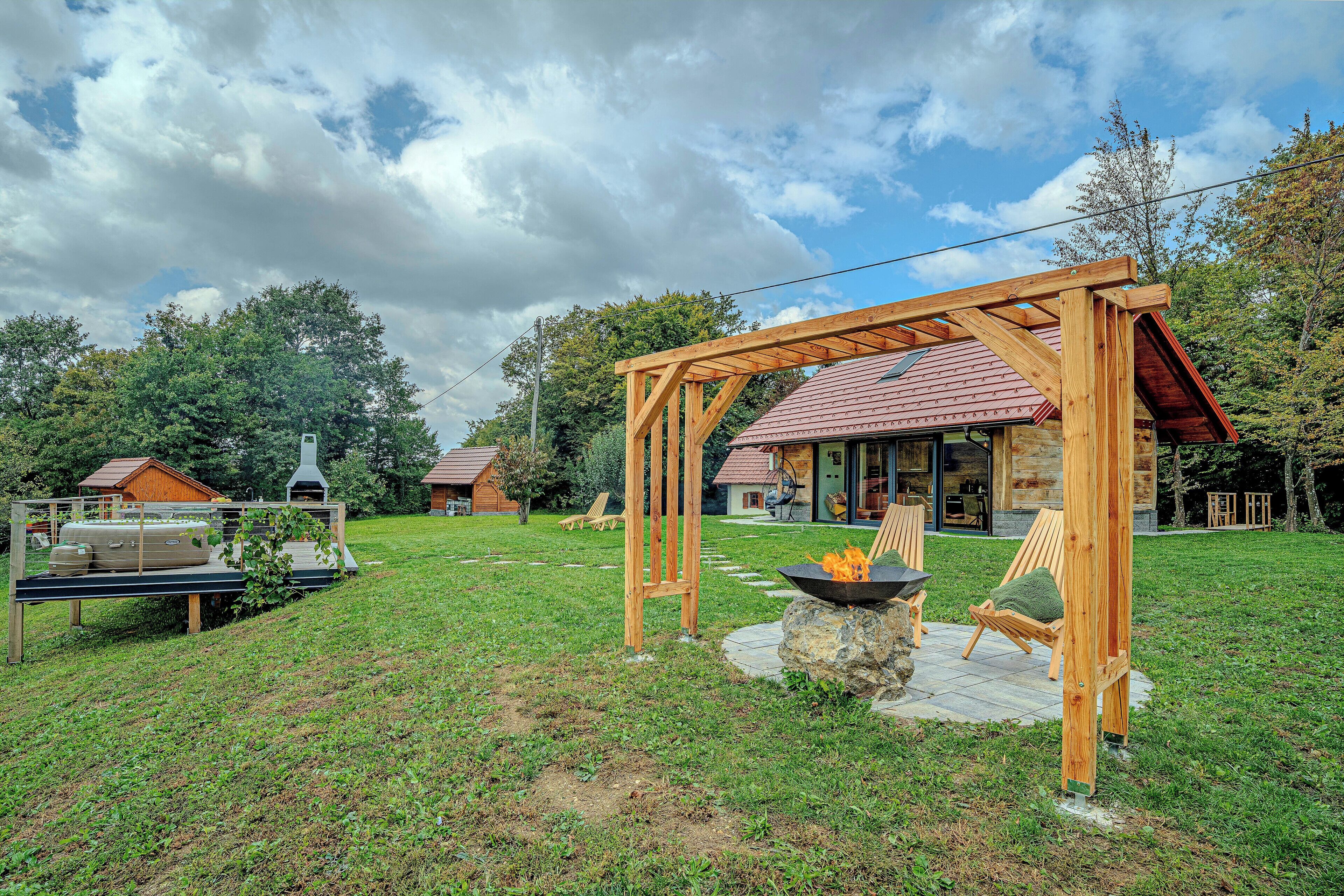 Eine hölzerne Pergola im Hinterhof mit einem Steinkamin und Gartenmöbeln.