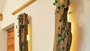 Two wooden wall art pieces with vines, illuminated by embedded lighting, in a hallway with wooden flooring and a wooden door. - Vineyard cottage Pri mali luži (Mokronog-Trebelno)
