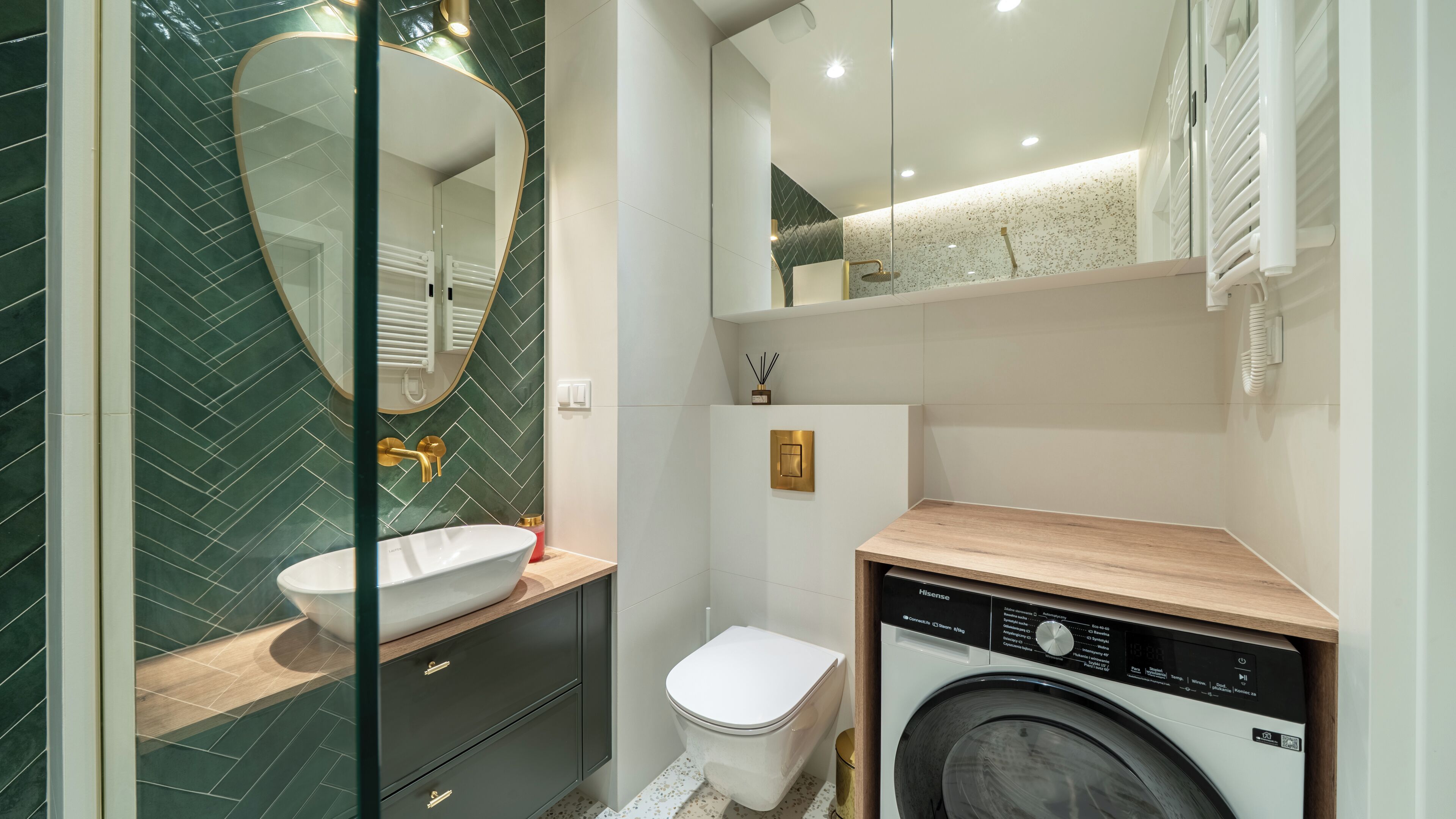 Un baño moderno con cabina de ducha de vidrio, un lavabo blanco y una lavadora integrada.