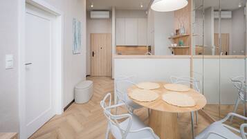 A modern kitchen with white cabinets, a wooden countertop, and a round table with four chairs.
