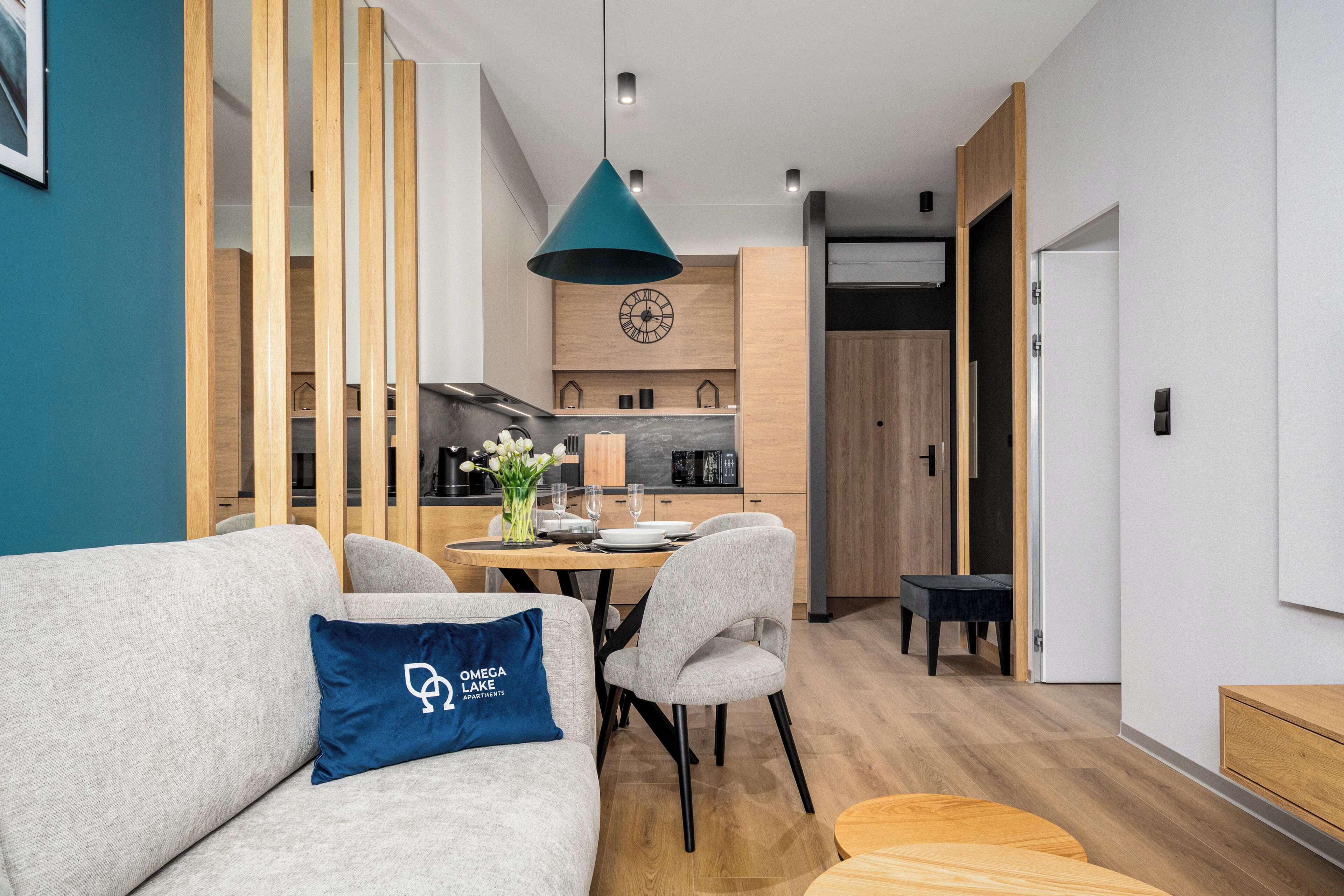 A modern living room with a sofa, a dining table, and a kitchen in the background.