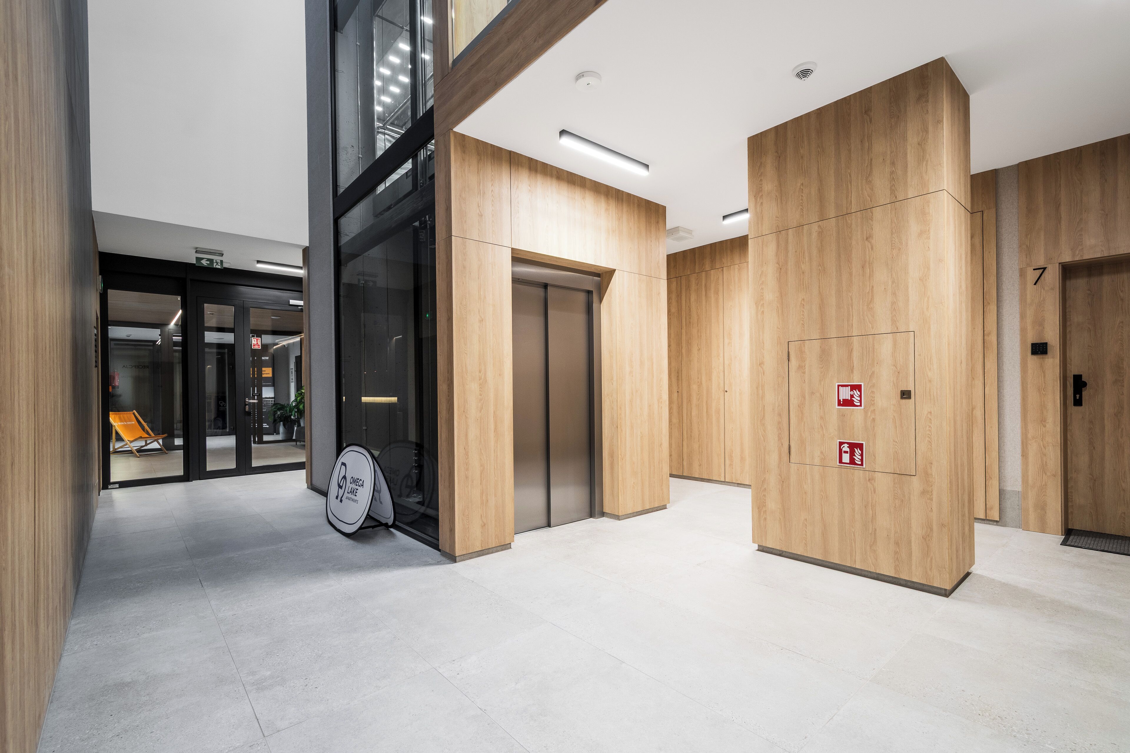 A modern interior with wooden paneling, a bike storage area, and an elevator.