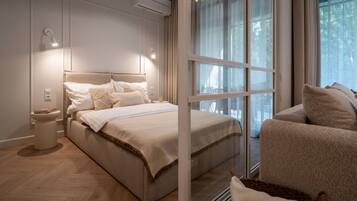 Un dormitorio moderno con una cama grande, mesitas de noche, una silla y una ventana con cortinas.