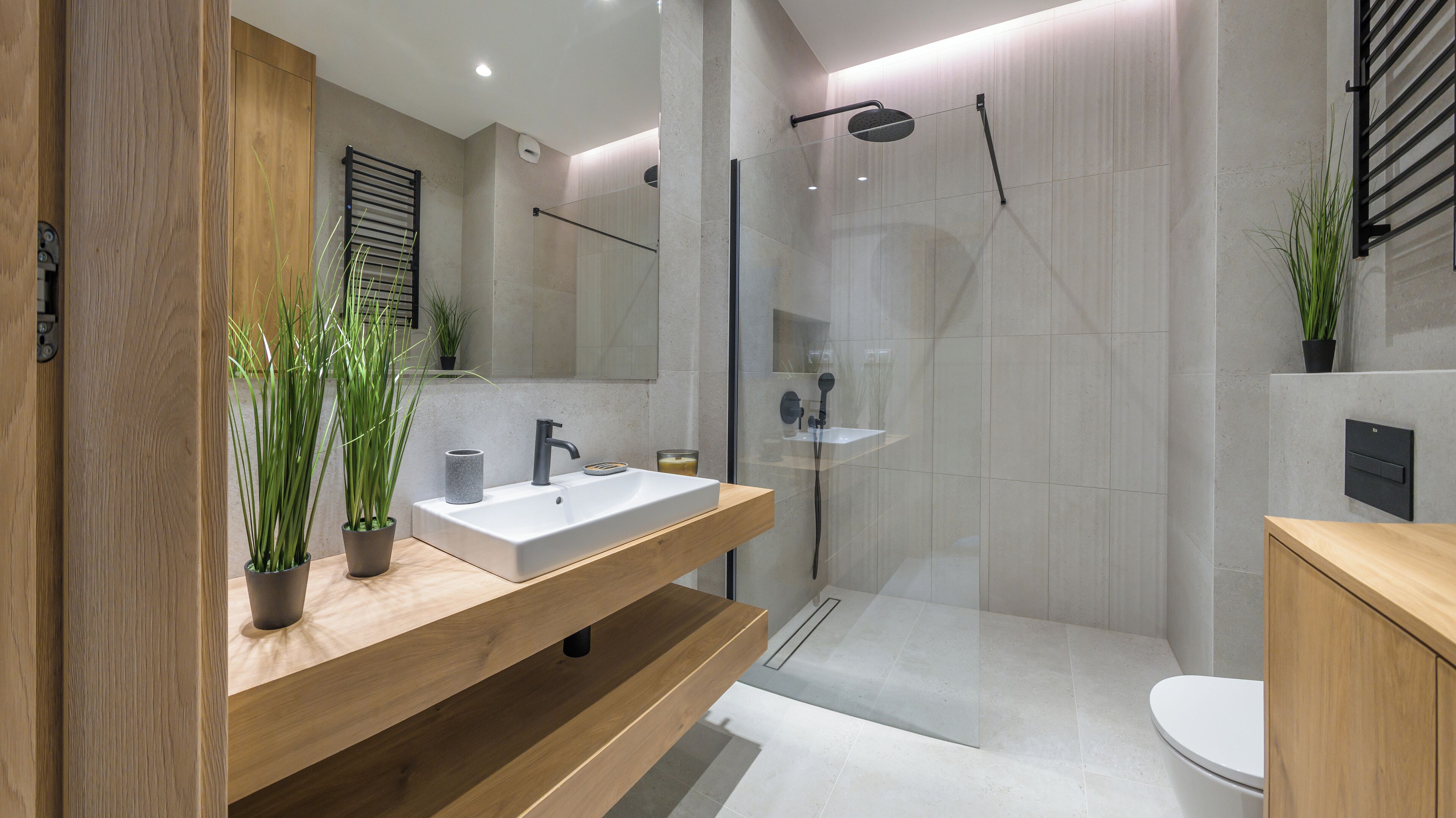 A modern bathroom with a wooden vanity, a glass shower enclosure, and a toilet.