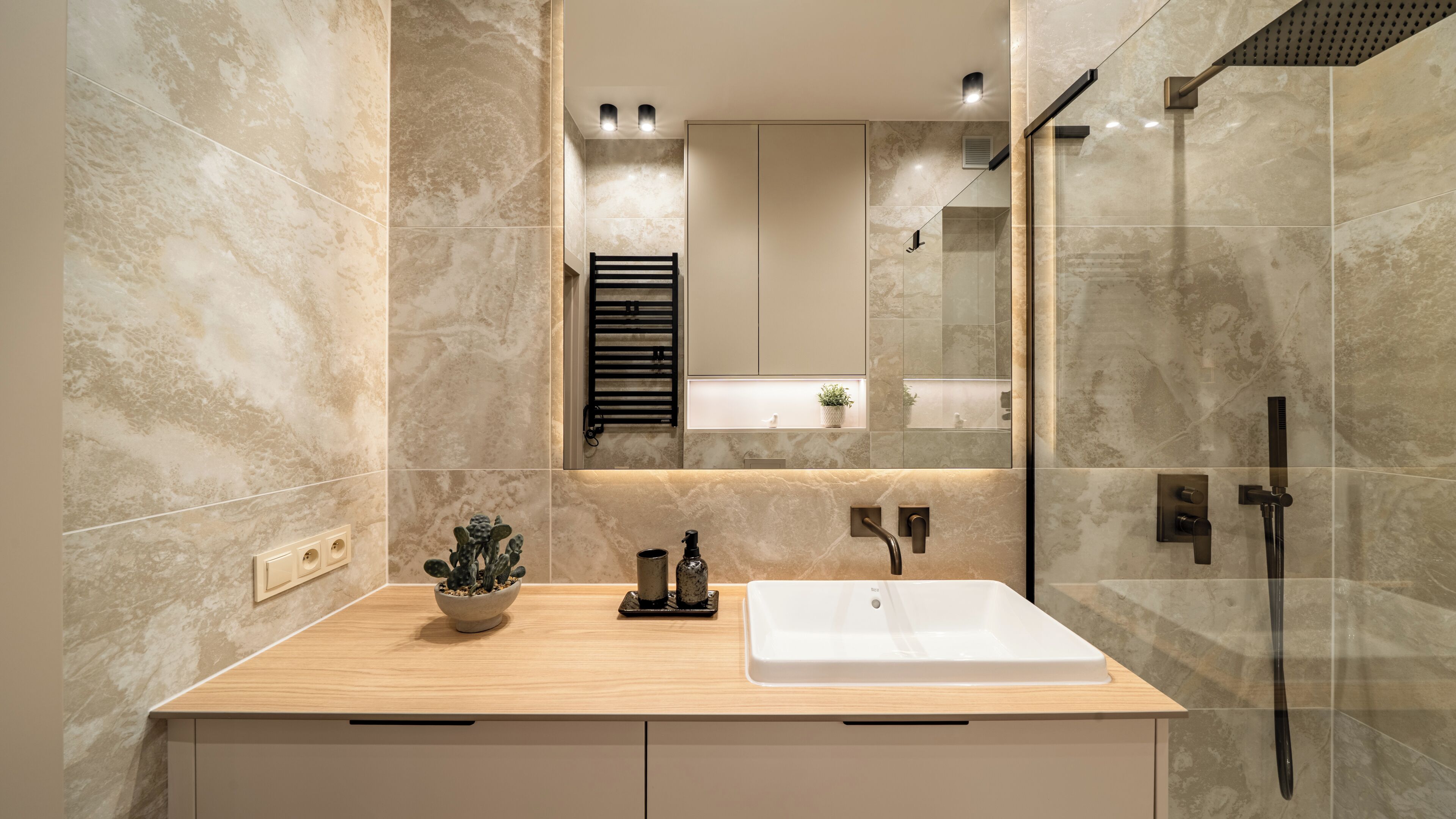 Une salle de bain moderne avec un grand miroir, un lavabo et une douche.