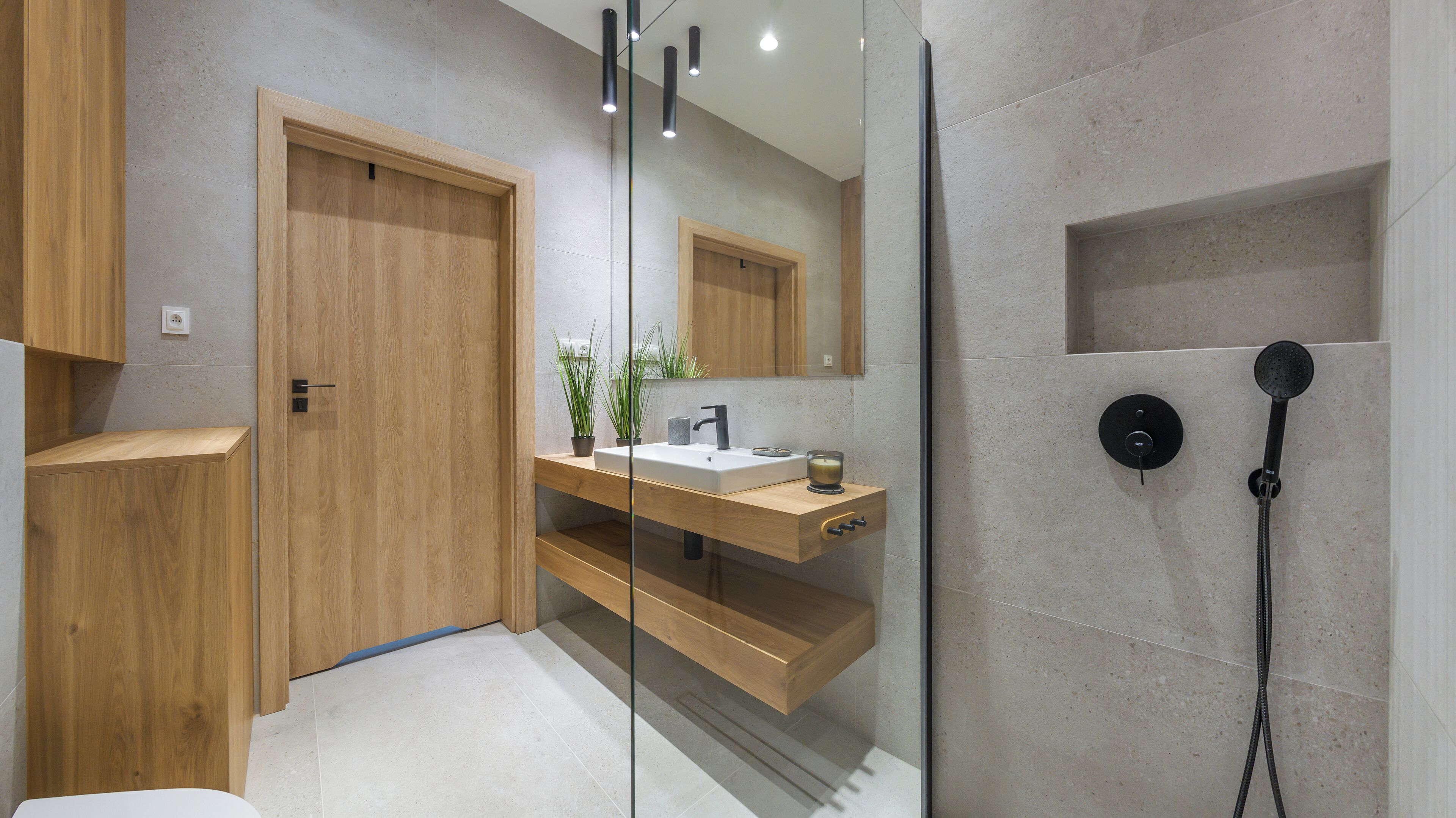 Une salle de bain moderne avec un meuble-lavabo en bois, une cabine de douche en verre et un lavabo intégré.