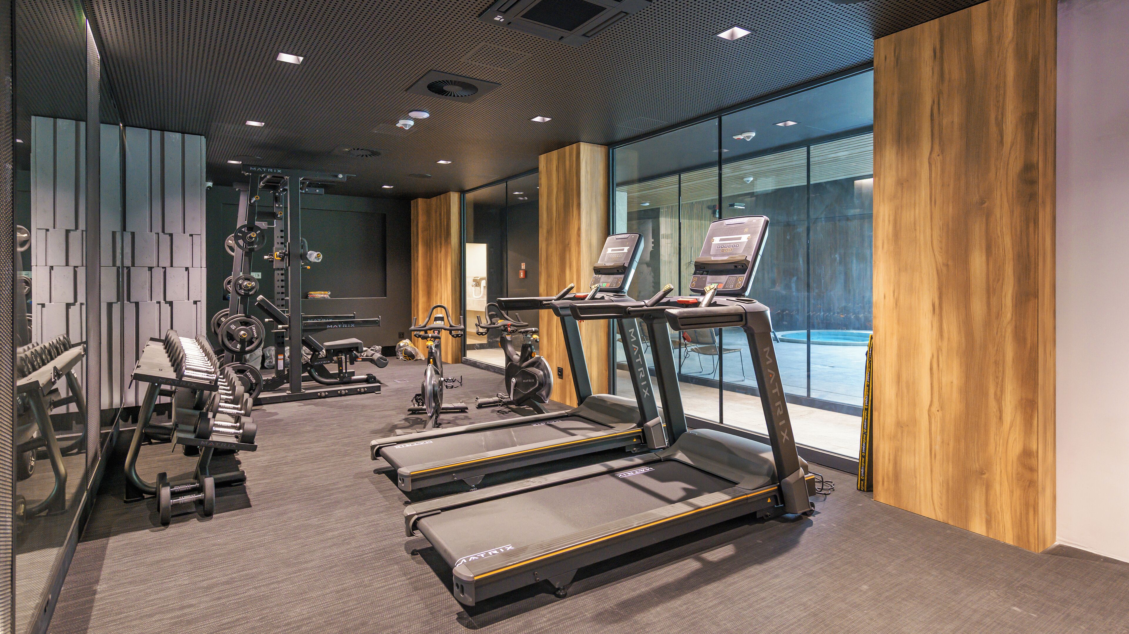 Un gimnasio moderno con cintas de correr, máquinas de pesas y una máquina de remo.