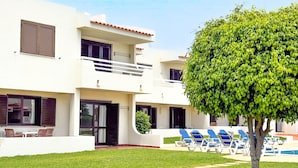 A two-story building with a balcony, a swimming pool, and a well-maintained lawn. - Aura Village City Beach Apartments (Albufeira)