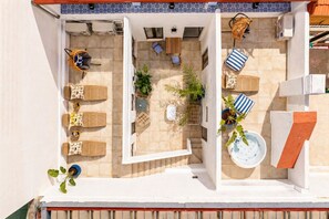 A rooftop terrace with a seating area, a hot tub, and potted plants.