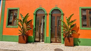 A building with two arched doorways, numbered 23 and 25, and large potted plants in front. - City-center townhouse with patio, Stylish 3 bedroom townhouse near Portimão promenade, 15 mins to Praia da Rocha. Private unit in historic building with shared patio, AC in all rooms, fast Wi-Fi, and modern comforts. (Portimao)