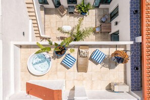 A rooftop terrace with a hot tub, lounge chairs, potted plants, and a pool table.