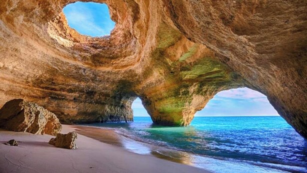 A natural rock formation with a circular opening and a beach in the foreground. - City-center townhouse with patio, Stylish 3 bedroom townhouse near Portimão promenade, 15 mins to Praia da Rocha. Private unit in historic building with shared patio, AC in all rooms, fast Wi-Fi, and modern comforts. (Portimao)