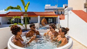 Un grupo de personas en un jacuzzi con vistas a edificios y un tejado de tejas rojas.
