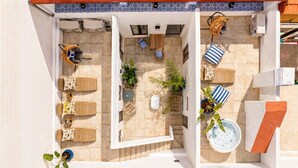 Una terraza en la azotea con zona de estar, jacuzzi y plantas en macetas.