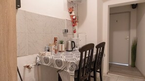 Uma área de refeições com uma mesa posta para dois, uma chaleira e diversos temperos.