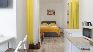 Quarto com cama, mesa de cabeceira e televisão.