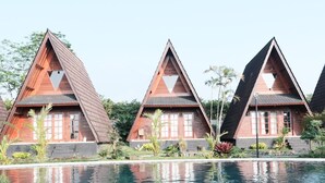 A row of triangular-roofed cabins with a swimming pool in the foreground. - Jambu Klutuk Resort (Parakan)