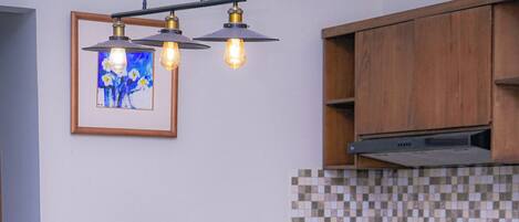 Eine moderne Küche mit Holzschränken, einer gefliesten Spritzschutzwand und einem Essbereich mit einem Glastisch und Holzstühlen.