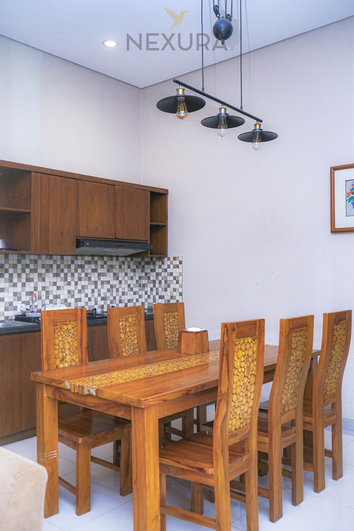 A dining area with a wooden table and chairs, a kitchen with wooden cabinets, and a tiled backsplash.