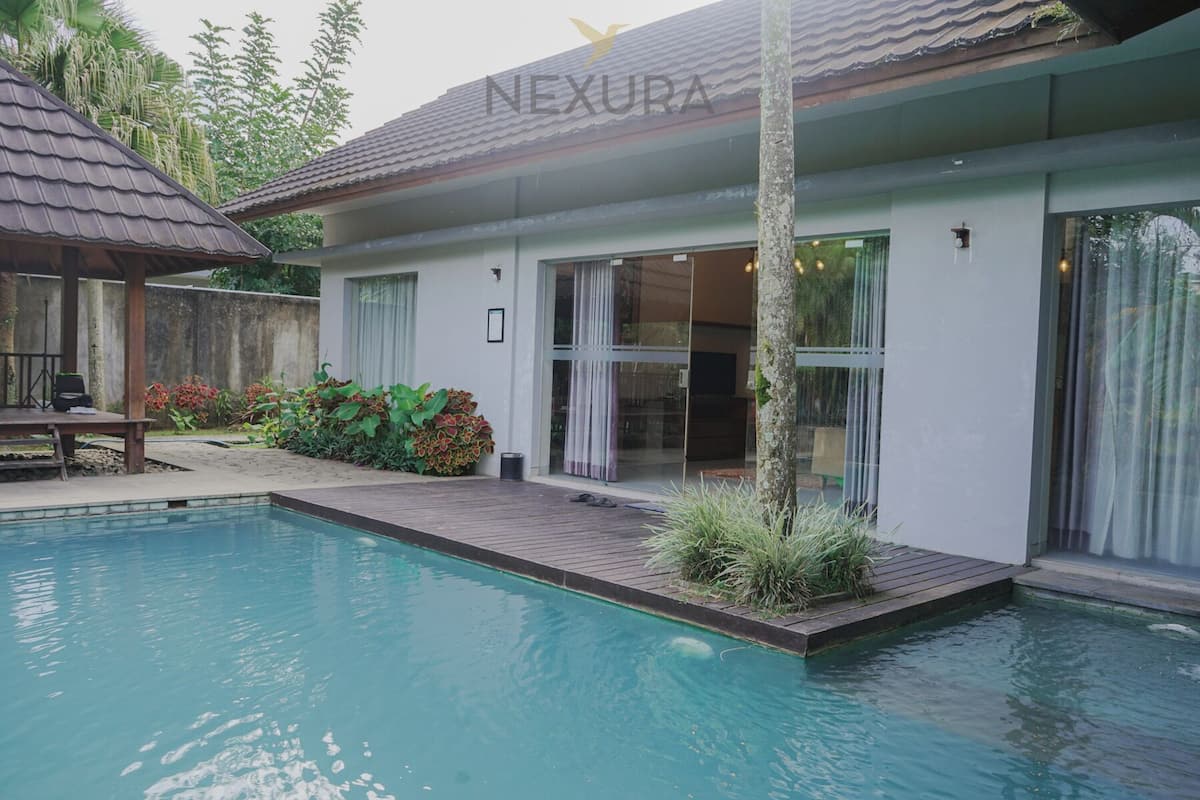 Une maison moderne dotée d’une piscine, d’un patio couvert et d’une grande porte vitrée.