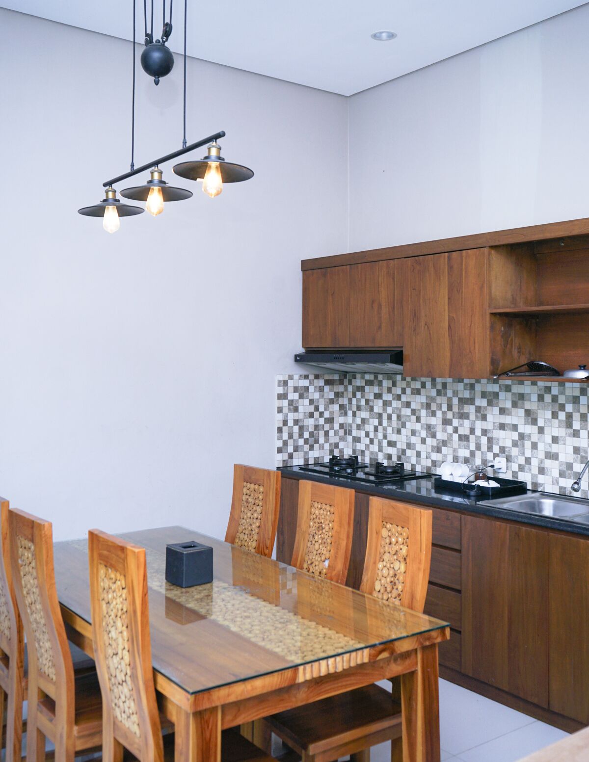 A modern kitchen with wooden cabinets, a tiled backsplash, and a glass dining table with chairs.