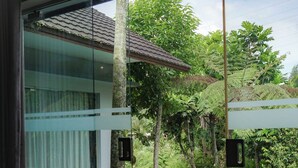 A modern glass door leading to a pool area with a wooden deck, surrounded by lush greenery. - Jambu Klutuk Resort (Parakan)