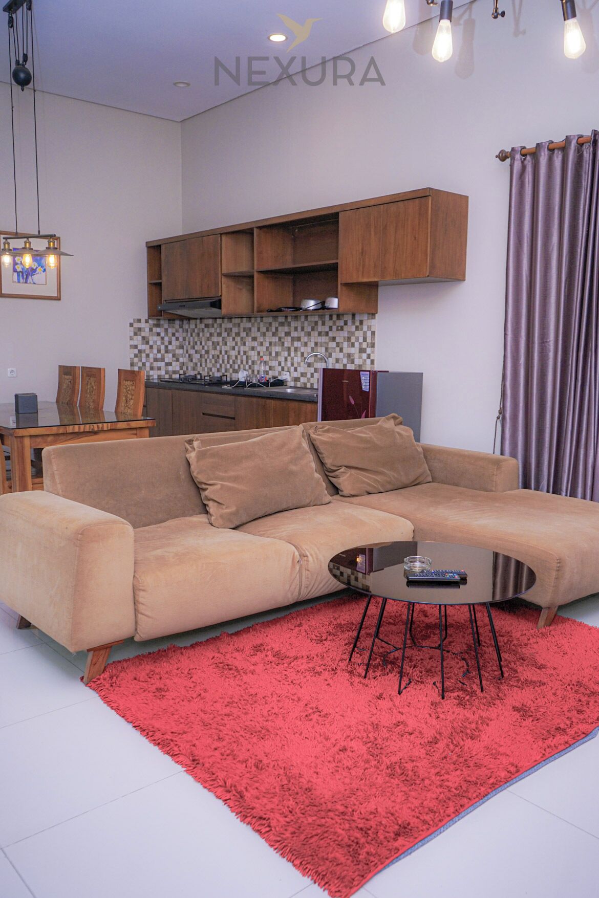 A modern living room with a beige sofa, a red shag rug, and a glass coffee table.