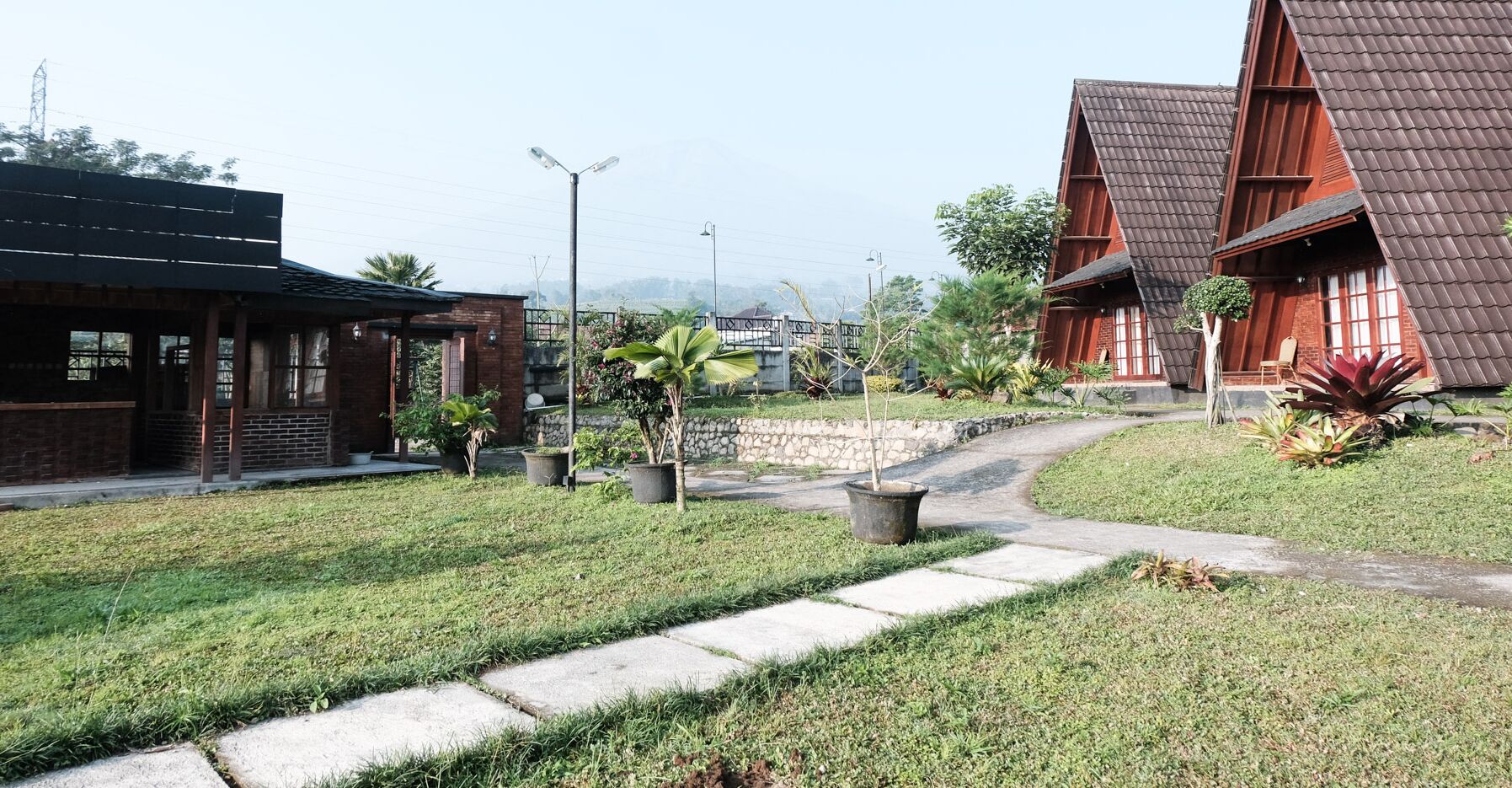A residential area with a paved pathway, brick buildings, and potted plants.