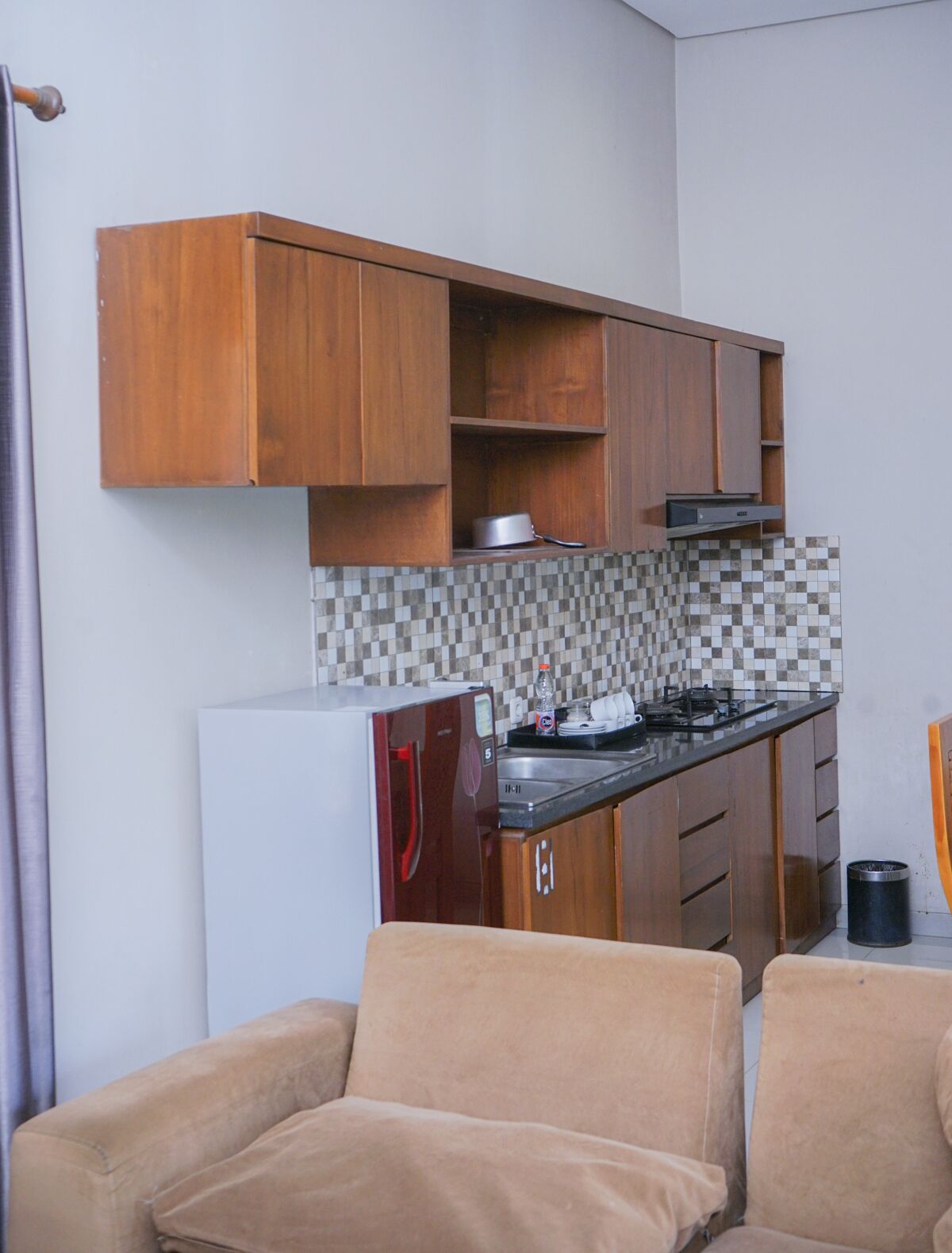 A compact kitchen with wooden cabinets, a tiled backsplash, a built-in stove, and a refrigerator.